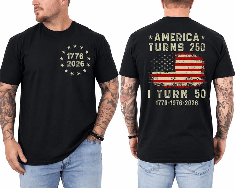 Op de afbeelding: Zwart T-shirt met de tekst "1776 2026" omringd door sterren op de voorkant. De achterkant van het shirt heeft een versleten Amerikaans vlagontwerp met de tekst "AMERICA TURNS 250" en "I TURN 50" met de data 1776-1976-2026.