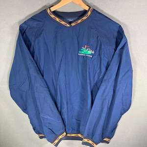 May include: Navy blue pullover windbreaker with a V-neck and long sleeves. The collar and hem feature a brown and gold pattern. The text "The Tips Radrick Farms" is embroidered on the left chest in green and white.