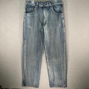 May include: Acid wash denim jeans with a straight leg cut. The jeans have a classic five-pocket design and a button and zipper closure. The denim has a vertical striped pattern and a light blue wash.
