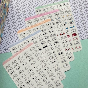 May include: Five sticker sheets with various emoji designs. Each sheet has a different colored header with the text "Annotating Emojis". The emojis are black and white and include a variety of expressions and symbols.