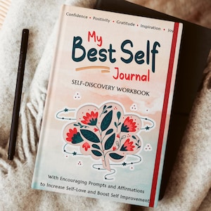 May include: A pink and white journal with a red border and a floral illustration. The cover reads "My Best Self Journal" and "Self-Discovery Workbook". The text also includes "With Encouraging Prompts and Affirmations to Increase Self-Love and Boost Self Improvement."