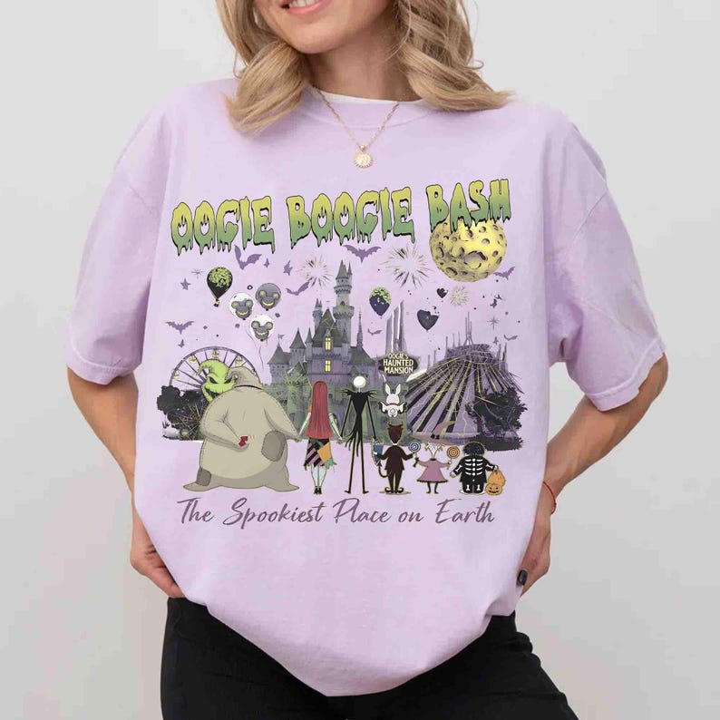 Puede incluir: Una camiseta de color morado claro con un estampado gr&aacute;fico que incluye el texto OOGIE BOOGIE BASH y The Spookiest Place on Earth. El dise&ntilde;o muestra un castillo, una luna, una noria y varios personajes animados en fila.