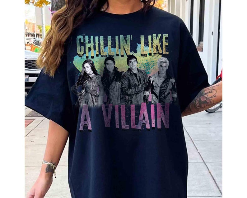 May include: Navy blue t-shirt with the text "CHILLIN' LIKE A VILLAIN" in a colorful, distressed font. The shirt features a graphic of four people. The overall design has a vintage, faded look.
