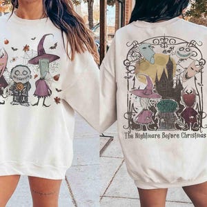 Puede incluir: Sudadera color crema con un gr&aacute;fico de "Pesadilla antes de Navidad". La parte delantera muestra tres personajes con un sombrero de bruja, y la trasera un castillo y el texto "The Nightmare Before Christmas."