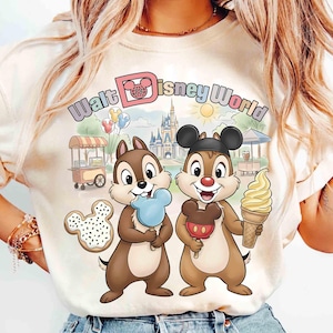 May include: Cream-colored t-shirt featuring Chip and Dale holding treats in front of a Walt Disney World scene. The shirt has the words "Walt Disney World" in a colorful font. A Mickey Mouse-shaped cookie and a soft-serve ice cream cone are also visible.