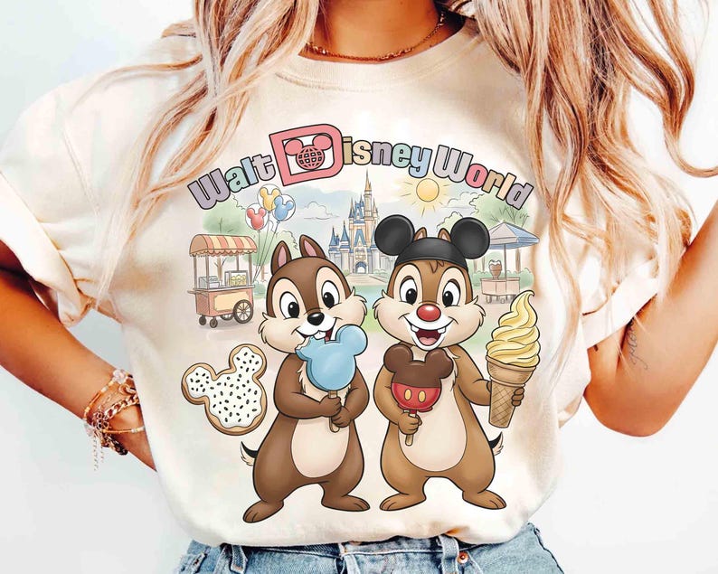 May include: Cream-colored t-shirt featuring Chip and Dale holding treats in front of a Walt Disney World scene. The shirt has the words "Walt Disney World" in a colorful font. A Mickey Mouse-shaped cookie and a soft-serve ice cream cone are also visible.