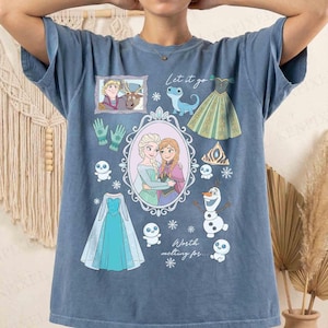 Könnte beinhalten: Blaues T-Shirt mit Illustrationen aus dem Film "Die Eiskönigin". Das Design zeigt Anna, Elsa, Olaf und andere Symbole, mit den Texten "Let it go" und "Worth melting for."