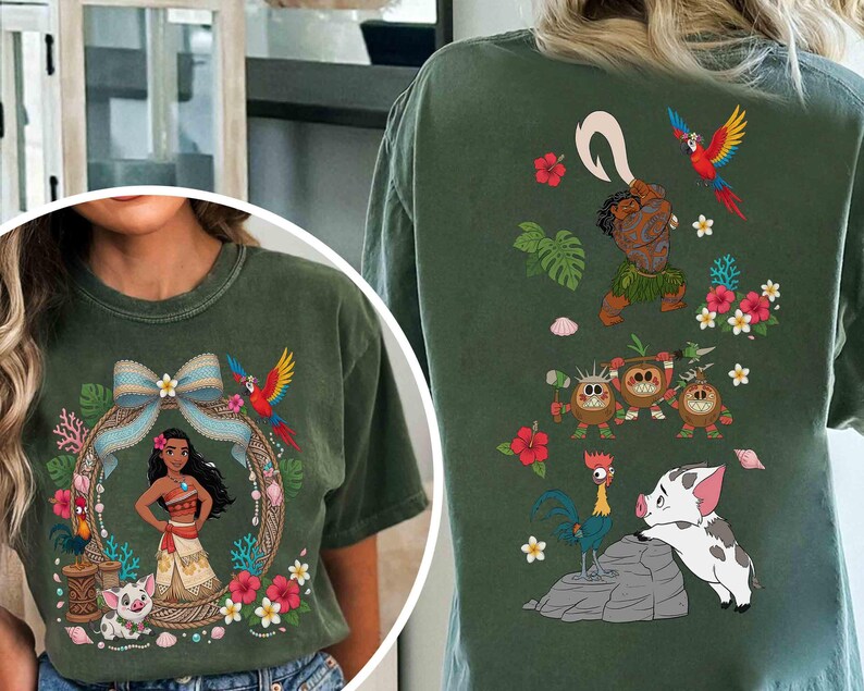 May include: A dark olive green t-shirt featuring a front graphic of a female character with long dark hair, a blue bow, a parrot, and a piglet. The back graphic displays a male character with a hook, three coconut creatures, a rooster, and a piglet.