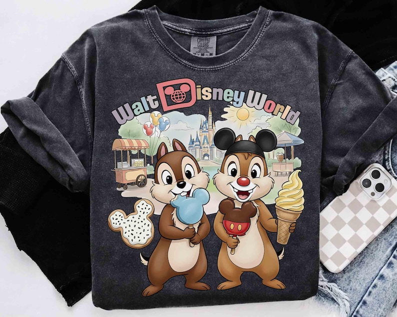 May include: Dark gray t-shirt featuring Chip and Dale with ice cream cones and a Mickey Mouse cookie. The shirt has the words "Walt Disney World" in a colorful design, with a castle and other park elements.
