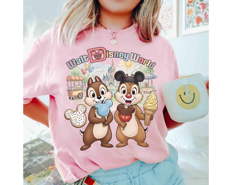 May include: Pink t-shirt with a colorful graphic featuring Chip and Dale holding ice cream treats in front of a Walt Disney World scene. The shirt also has the words "Walt Disney World" in pastel colors.