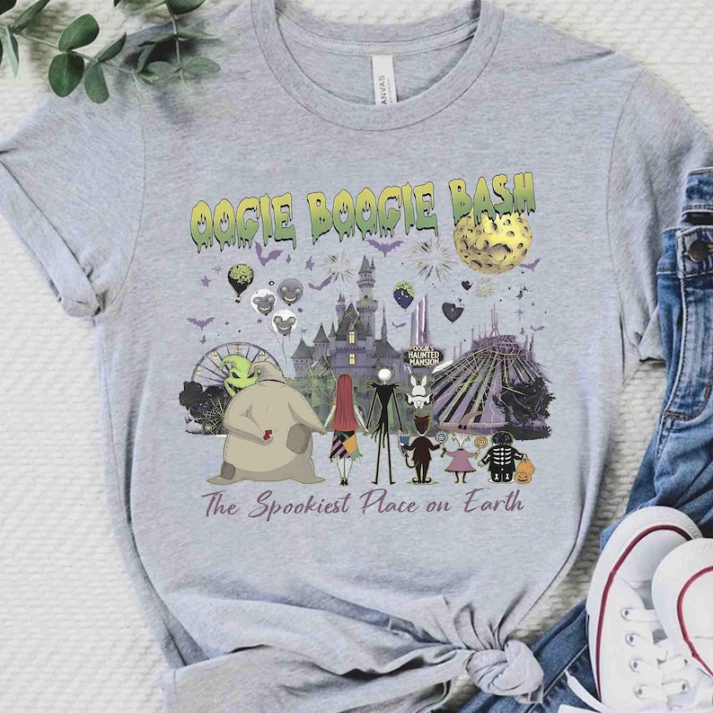 Puede incluir: Una camiseta gris jaspeado con un estampado gr&aacute;fico que incluye el texto OOGIE BOOGIE BASH y The Spookiest Place on Earth. El dise&ntilde;o muestra personajes de Pesadilla antes de Navidad, un castillo, una luna y varios iconos de Halloween.