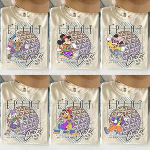 May include: Cream-colored t-shirts featuring various Disney characters in front of a geometric sphere design. Each shirt has the text "EPCOT" and "Merter 1982" printed on it. The characters include Donald Duck, Mickey Mouse, Minnie Mouse, Daisy Duck, Goofy, and Pluto.