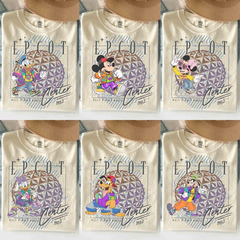 May include: Cream-colored t-shirts featuring various Disney characters in front of a geometric sphere design. Each shirt has the text "EPCOT" and "Merter 1982" printed on it. The characters include Donald Duck, Mickey Mouse, Minnie Mouse, Daisy Duck, Goofy, and Pluto.