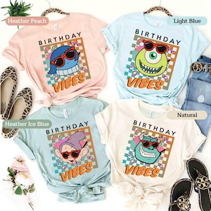 May include: Four pastel-coloured t-shirts, each featuring a cartoon character wearing sunglasses and the words "BIRTHDAY VIBES". The shirts are in heather peach, light blue, heather ice blue, and natural. The design has a retro feel.