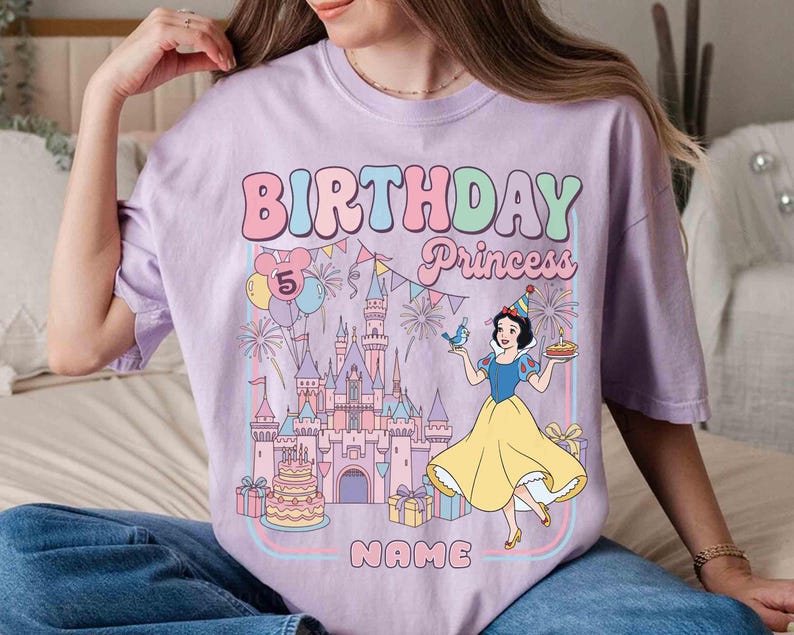 May include: Lilac t-shirt with a colourful graphic design. The design features the words "BIRTHDAY Princess" in bubble letters, a castle, and a cartoon of Snow White. The number 5 is displayed with balloons.