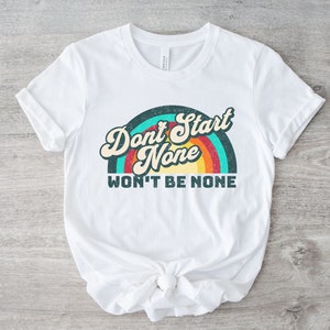 May include: White t-shirt with a retro rainbow graphic and the text "Don't Start None Won't Be None".