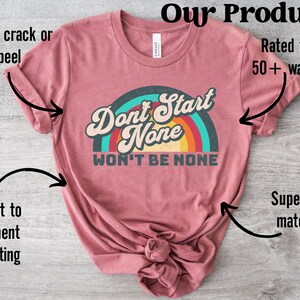 May include: A maroon t-shirt with a rainbow graphic and the text "Don't Start None Won't Be None". The shirt is made of a super soft material and is rated for 50+ washes.