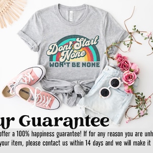May include: A gray t-shirt with a rainbow graphic and the text "Don't Start None Won't Be None". The shirt is paired with denim shorts, pink sneakers, and sunglasses.