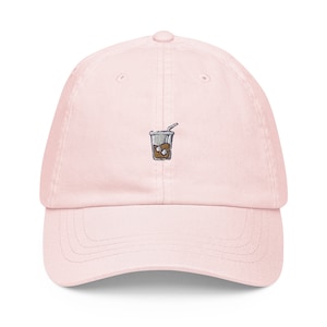 May include: A pink baseball cap with an embroidered image of a cup of iced coffee with a straw.