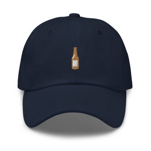 May include: A navy blue baseball cap with a brown embroidered beer bottle design.