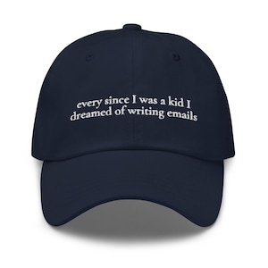 May include: Navy blue baseball cap with white embroidered text that reads "every since I was a kid I dreamed of writing emails"