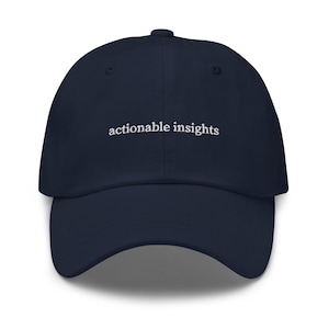 Pode incluir: Um boné de beisebol azul-marinho com o texto actionable insights bordado em fio branco no painel frontal. O boné possui uma copa estruturada, aba curva e um botão no topo, apresentando um design limpo e simples para o uso diário.