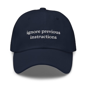 Op de afbeelding: Marineblauwe baseballcap met de witte, geborduurde tekst "ignore previous instructions". De cap heeft een gebogen klep en een gestructureerde pasvorm, geschikt voor casual wear.