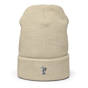 May include: A beige waffle knit beanie with a small embroidered image of a coffee pot.