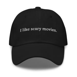 Peut inclure: Casquette de baseball noire avec une visière incurvée. Le texte brodé "I like scary movies." en blanc est centré sur le devant. La casquette a une coupe structurée et un bouton sur le dessus.