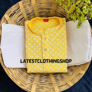 May include: A yellow kurta with a white geometric pattern and a white button-up collar. The kurta is on a woven basket with a white fabric underneath. The text "LATESTCLOTHINGSHOP" is visible on the fabric.