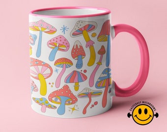 May include: A pink ceramic mug with a white interior and a pink handle. The mug features a colorful illustration of mushrooms with a retro design. The text "East Coast Mushrooms" is printed on the bottom of the mug.