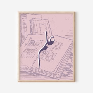 May include: A framed print featuring a pink and purple illustration. The artwork depicts an open book with Arabic calligraphy in a dark purple hue. The background shows stacks of books in a similar color palette.