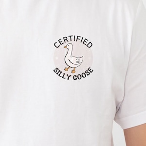 May include: White t-shirt with a graphic of a goose and the text "CERTIFIED SILLY GOOSE" in a circle.