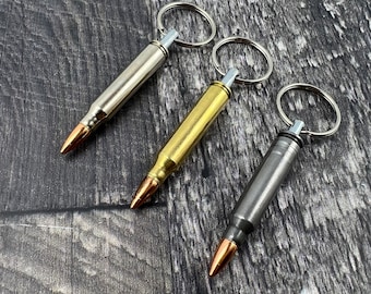 May include: Three bullet-shaped keychains with different finishes: silver, gold, and black. Each keychain has a split ring for attaching keys.