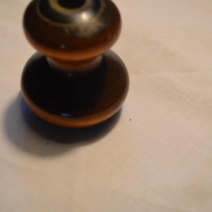 Könnte beinhalten: Ein zweiteiliger Holzknauf mit dunkelbraunem Finish. Das Oberteil hat ein kreisförmiges Design mit konzentrischen Ringen. Der Knauf ist wahrscheinlich für eine Schublade oder einen Schrank und besteht aus Holz.