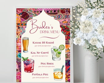 May include: A framed "Bride's Drink Menu" with a colorful, patterned background. The menu features watercolor illustrations of cocktails and the names "Kanak Di Rakhi", "Kal Nu Chuti", "Peg Sheg", and "Patiala Peg". A vase of white flowers is to the right.