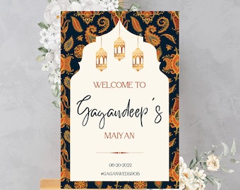 May include: Welcome to Gagandeep's Maiyan wedding sign with a blue and gold paisley pattern and gold lanterns. The date 06-20-2022 and hashtag #GAGANWEDSR0B are printed at the bottom.