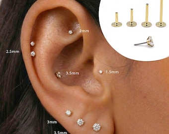 May include: A collection of gold-tone flat back labret stud earrings featuring clear round-cut stones. The set includes various post lengths and stone diameters ranging from 1.5mm to 4mm, displayed both as individual components and worn in an ear.