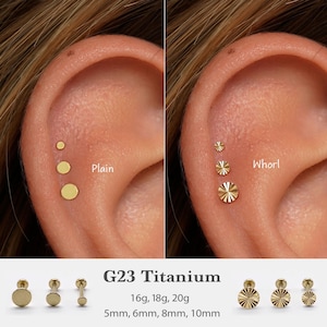 Peut inclure: Gros plan de deux oreilles percées de plusieurs boucles d'oreilles en titane doré. Une oreille présente trois clous ronds et lisses. L'autre oreille affiche trois boucles d'oreilles en forme de spirale. Le texte indique "G23 Titanium" et les tailles.