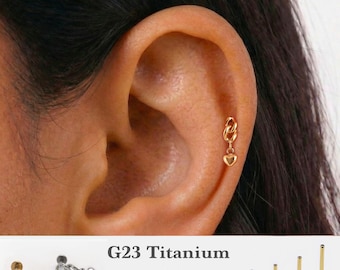 Könnte beinhalten: Ein goldfarbener Ohrring mit Herzanhänger und Kettengliedern. Der Text G23 Titanium, 16g, 18g, 20g sowie 5mm, 6mm, 8mm, 10mm ist zu sehen. Der Ohrring ist an einem Knorpelpiercing angebracht, neben silbernen und goldenen Ausführungen.