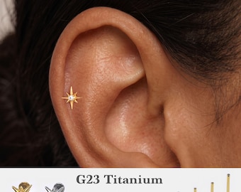 May include: A gold-colored starburst-shaped cartilage earring with a central clear stone. The text G23 Titanium, 16g, 18g, 20g, and 5mm, 6mm, 8mm, 10mm is visible, along with four flat-back posts of varying lengths and a silver-colored version.