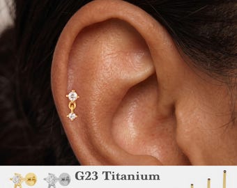 Könnte beinhalten: Ein goldfarbener Ohrstecker aus G23-Titan mit zwei klaren, rund geschliffenen Steinen, die durch ein kleines Glied verbunden sind. Der Text G23 Titanium, 16g, 18g, 20g sowie 5mm, 6mm, 8mm, 10mm und vier flache Steckerstifte sind zu sehen.