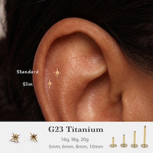 May include: Two gold-colored star-shaped flat back earrings are shown in an ear piercing. Text labels indicate Standard and Slim sizes. Additional text displays G23 Titanium, 16g, 18g, 20g, and lengths of 5mm, 6mm, 8mm, 10mm with four posts.