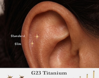 May include: Two gold-colored star-shaped flat back earrings are shown in an ear piercing. Text labels indicate Standard and Slim sizes. Additional text displays G23 Titanium, 16g, 18g, 20g, and lengths of 5mm, 6mm, 8mm, 10mm with four posts.