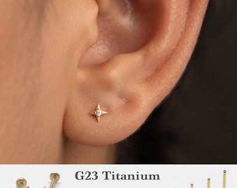 May include: A gold-tone star-shaped stud earring with a central clear stone. The G23 titanium jewelry is available in 16g, 18g, and 20g gauges with post lengths of 5mm, 6mm, 8mm, and 10mm, featuring a flat back design for secure ear placement.