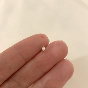 K&ouml;nnte beinhalten: Ein kleiner, birnenf&ouml;rmiger Diamant-Ohrstecker in einer goldenen Fassung.