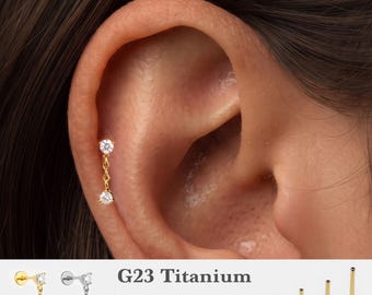 Könnte beinhalten: Ein goldfarbener Titan-Ohrstecker mit flacher Rückseite und einer hängenden Kette mit zwei klaren, runden Zirkonia-Steinen. Der Text G23 Titanium, 16g, 18g, 20g sowie 5mm, 6mm, 8mm, 10mm ist neben verschiedenen Stablängen und Farben abgebildet.