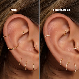 May include: Two images side-by-side showcasing gold hoop earrings. The left image displays plain gold hoops of varying sizes. The right image features gold hoops with a single line of clear cubic zirconia stones. The text "Plain" and "Single Line Cz" are visible.