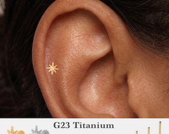 May include: A gold-toned starburst-shaped flat back stud earring with a central clear stone. The text G23 Titanium, 16g, 18g, 20g, and 5mm, 6mm, 8mm, 10mm is visible, along with gold and silver stud options and four post lengths.
