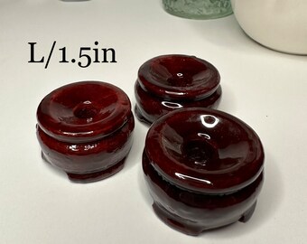 May include: Three dark red wooden display stands for crystals or other small objects. The stands are 1.5 inches in diameter. L/1.5in